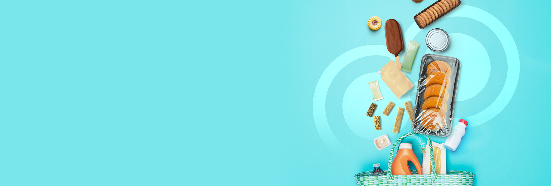 A variety of food and household items, including private label bread, canned goods, snacks, bottled drink, detergent, and cleaning supplies, spill out of a basket on a light blue background. A swirl design is subtly visible in the background.
